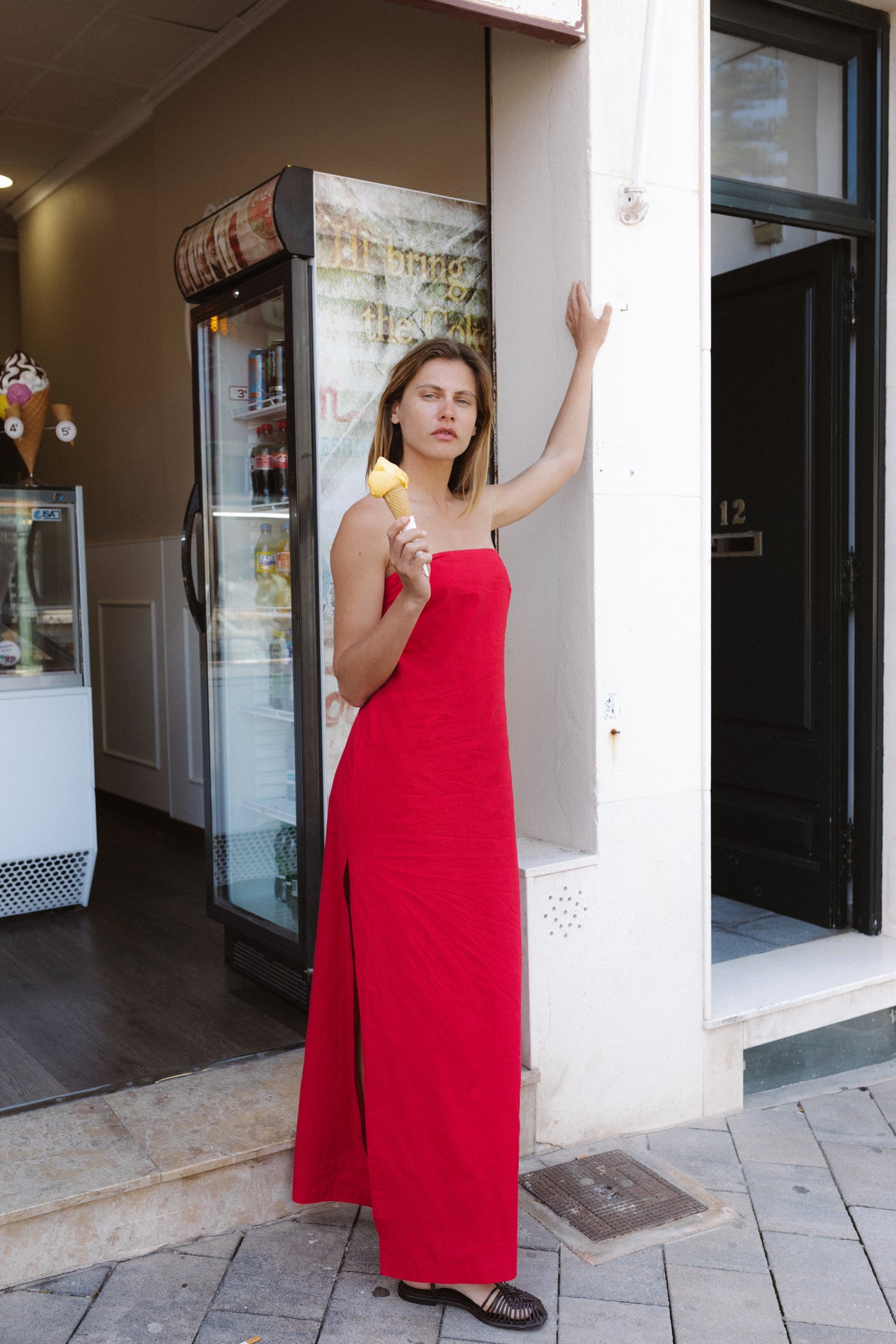 Woman in a red dress standing outside a building holding an ice cream