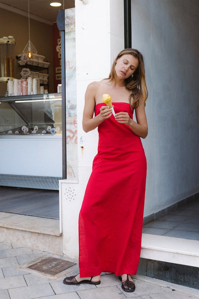 Woman in a red dress standing outside a store holding an ice crema 