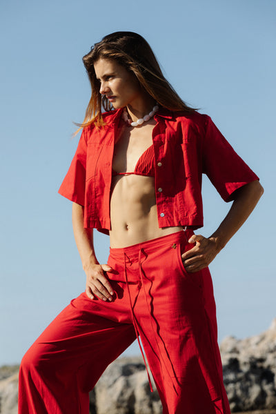 Woman in a red outfit standing outdoors with a clear blue sky.
