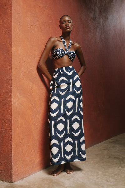 Woman wearing a patterned two-piece outfit against a textured wall.