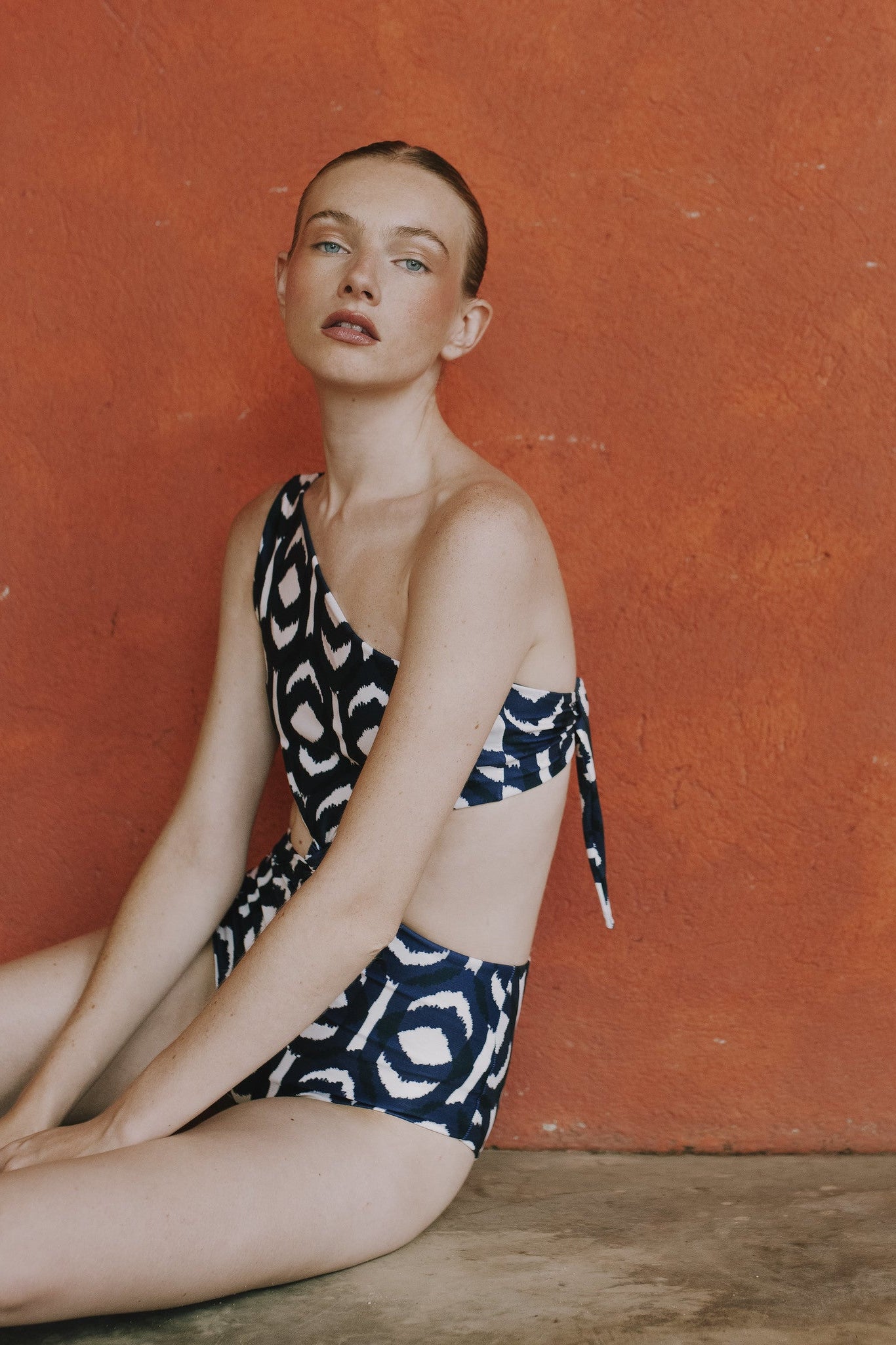 Lifestyle photo of Sabrina Ikat One Piece against terracotta wall.