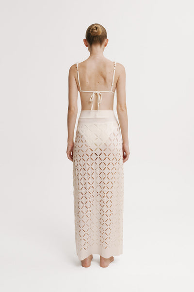 Woman wearing a beige dress with cut-out pattern on a white background