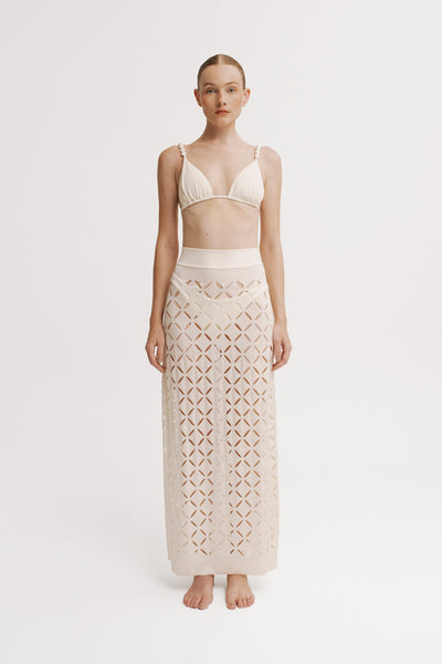 Woman wearing a beige crochet skirt and top on a white background