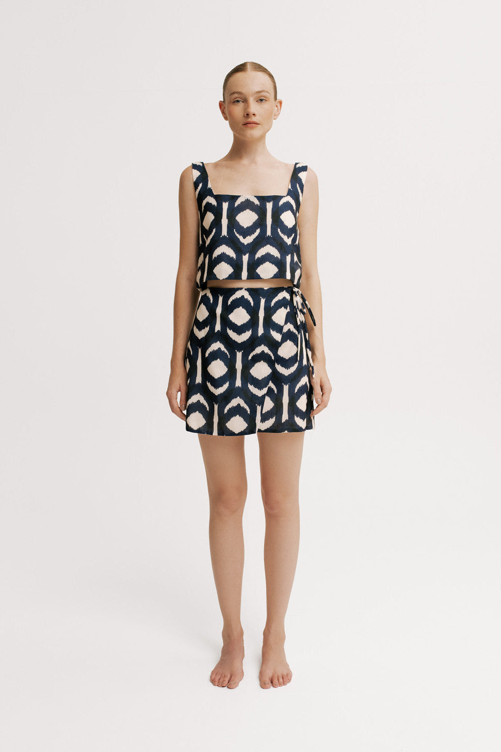 Woman wearing a navy and white patterned top and skirt on a white background