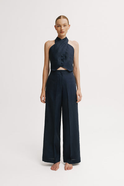 Woman wearing a navy halter top and wide-leg pants on a white background