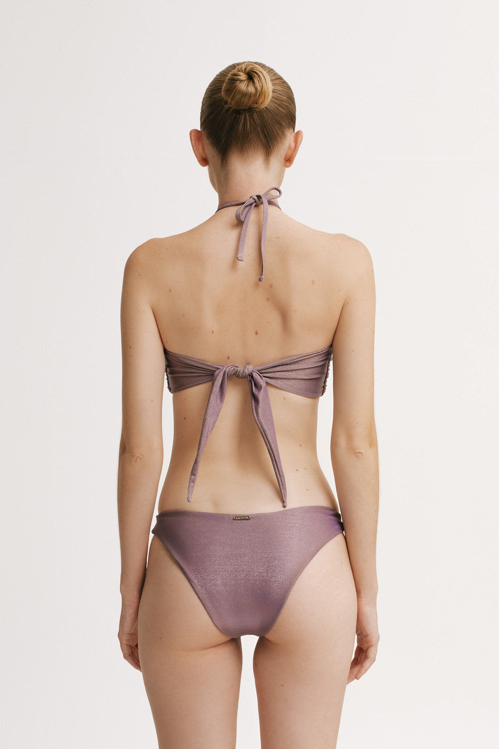 Woman wearing a purple bikini with a white background