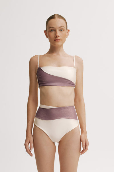 Woman wearing a two-tone swimsuit , LAVENDER AND IVORY with a plain background.