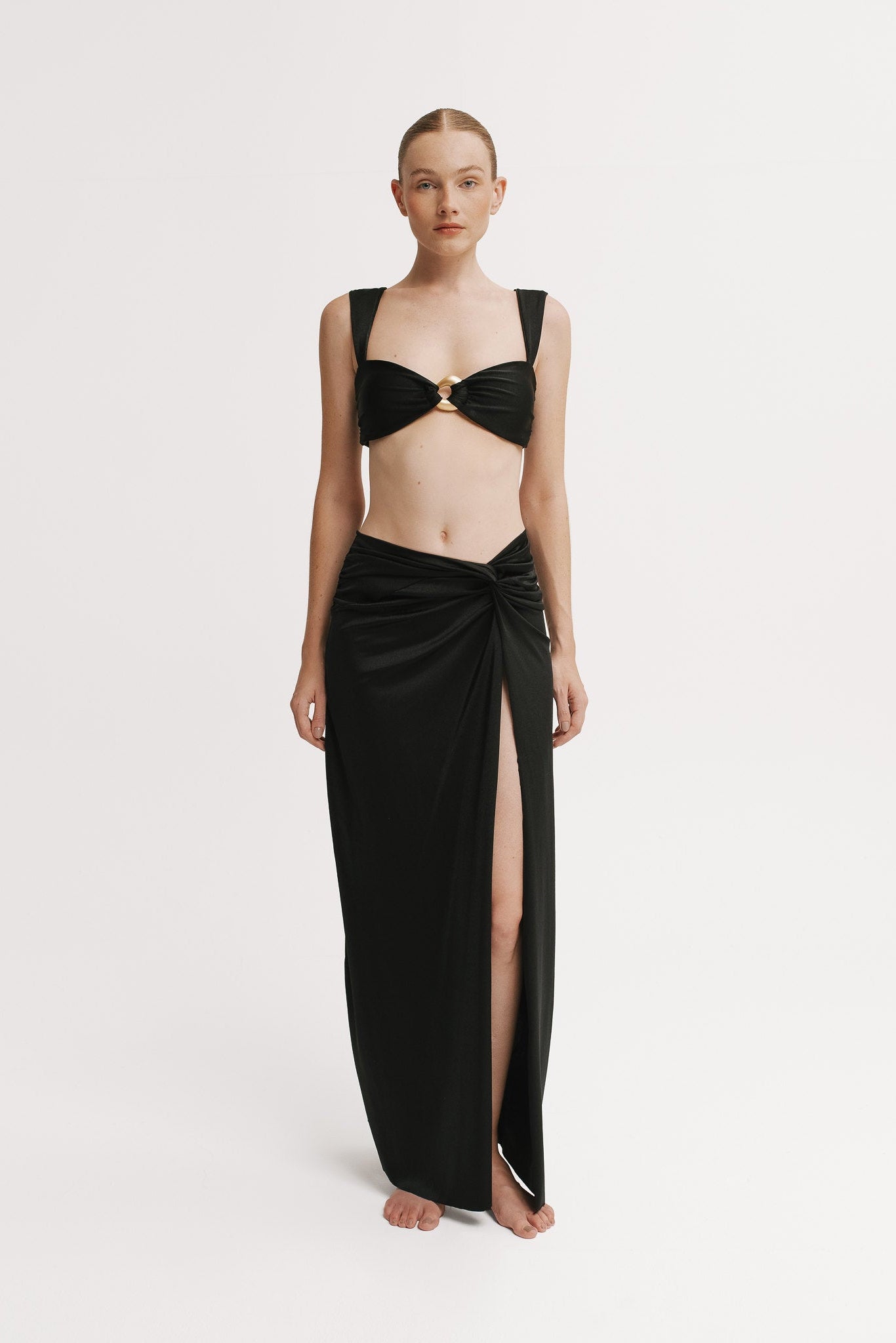 Front view of model wearing a Black maxi skirt with knotted waist and high slit