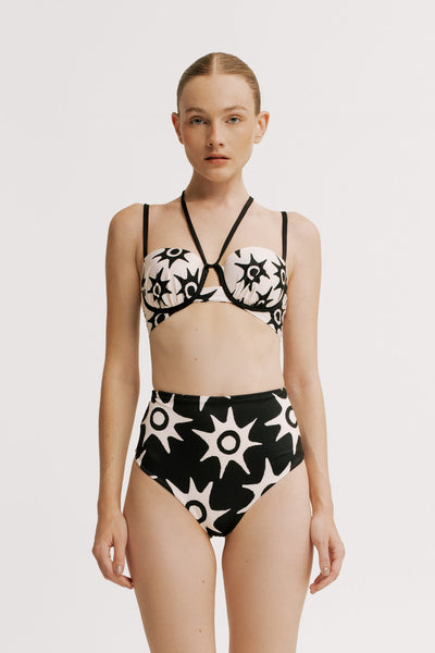 Woman wearing a black and white floral bikini on a plain background