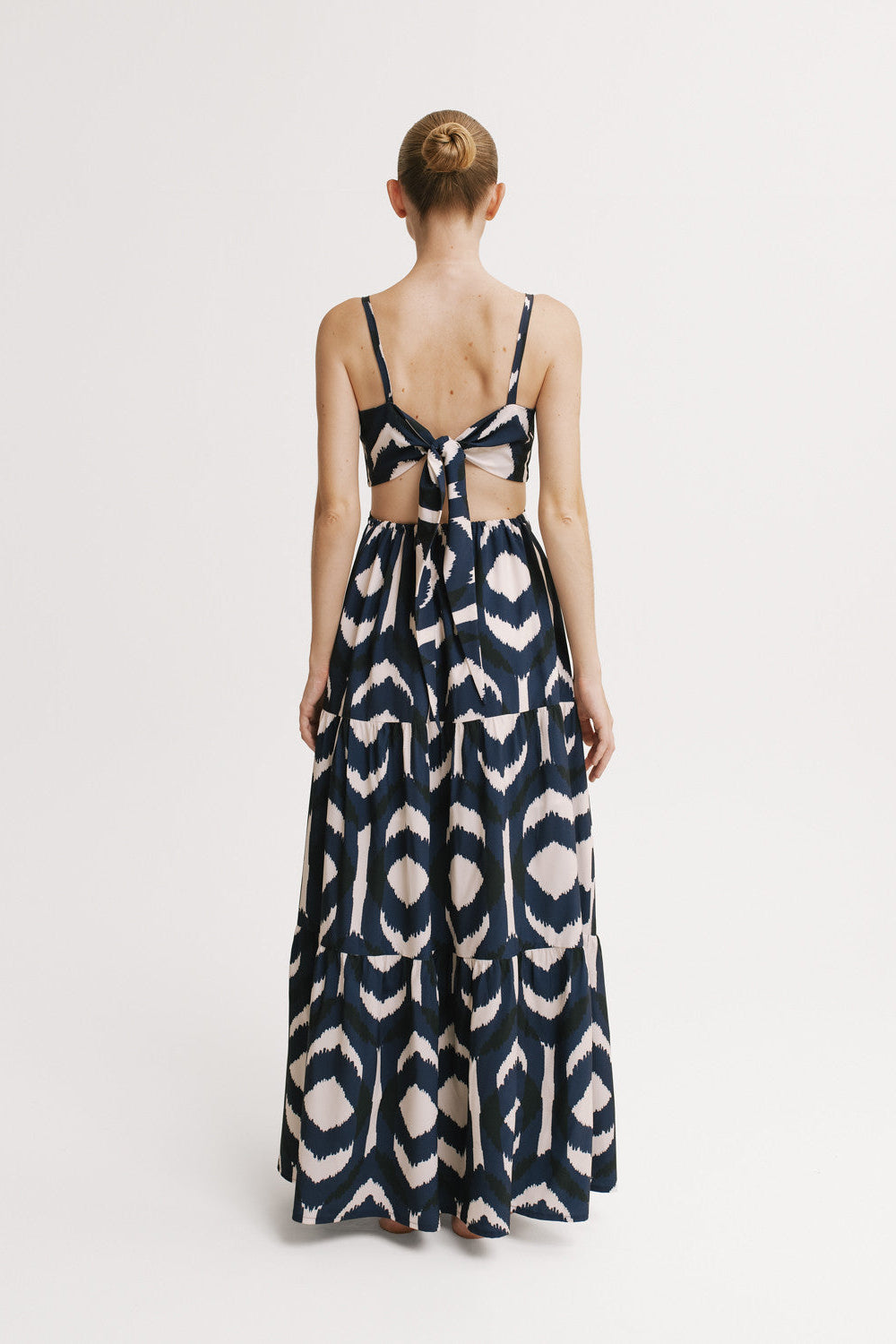 Woman wearing a patterned dress with cut-out design on a white background