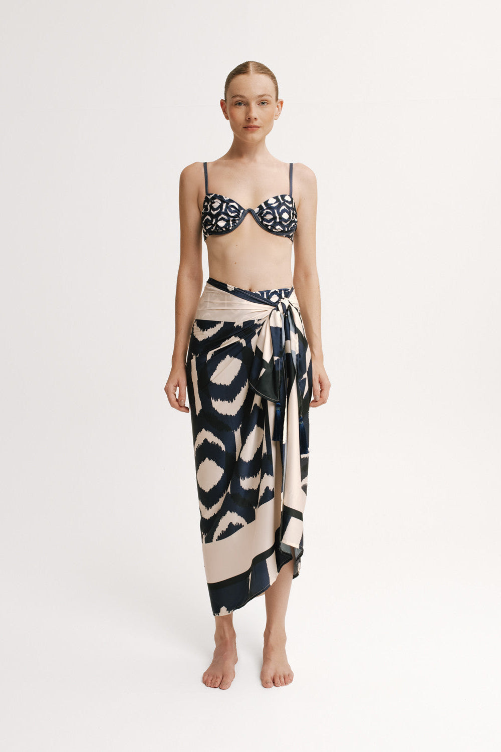 Woman wearing a black and white patterned bikini with a matching long skirt on a white background