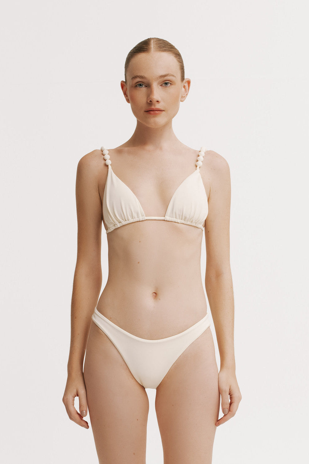 Woman wearing a beige bikini set on a plain background