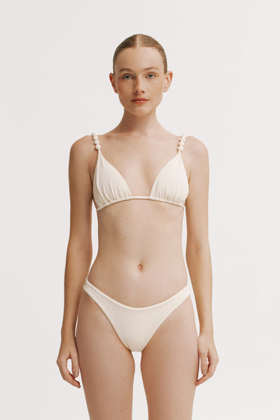 Woman wearing a beige bikini set on a plain background