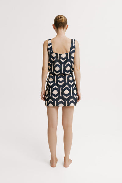 Woman wearing a sleeveless dress with a geometric pattern on a white background