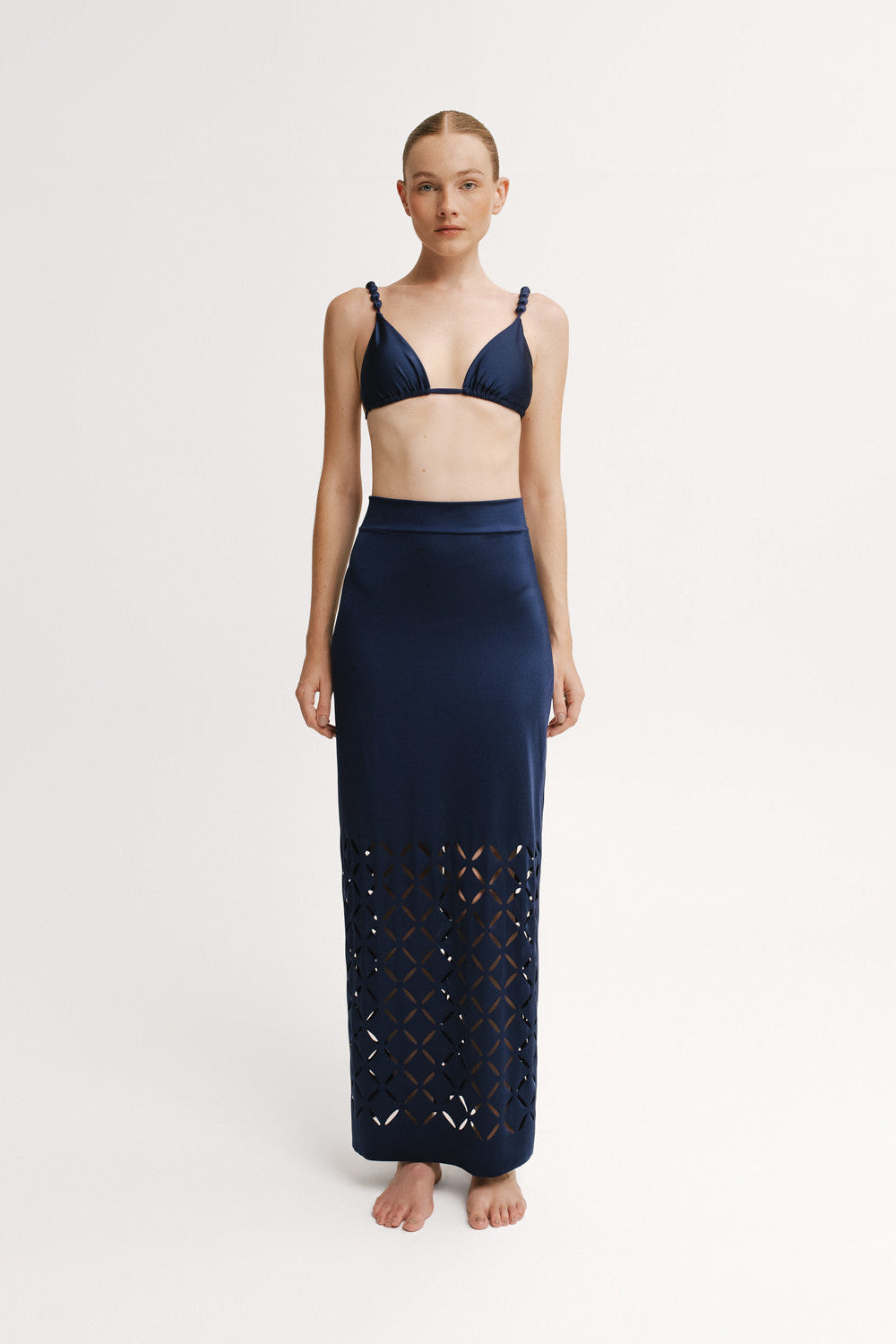 Full-length navy skirt with geometric laser-cut hem.