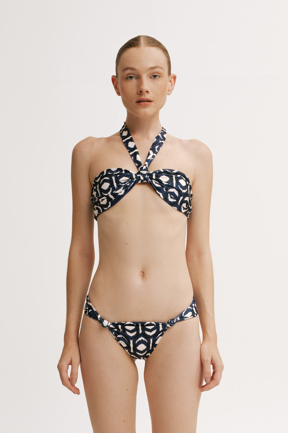 Front view of model wearing IKAT knot-front bandeau bikini top with halter tie