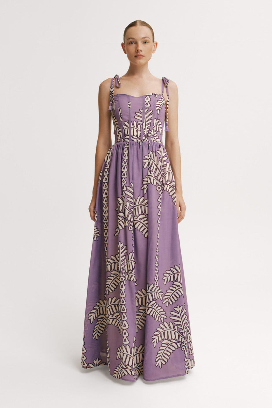 Model wearing a purple dress with gold leaf pattern on a white background