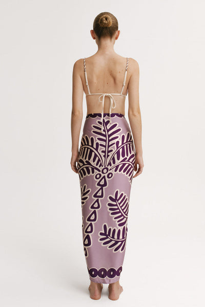 Woman wearing a purple patterned sarong on a white background