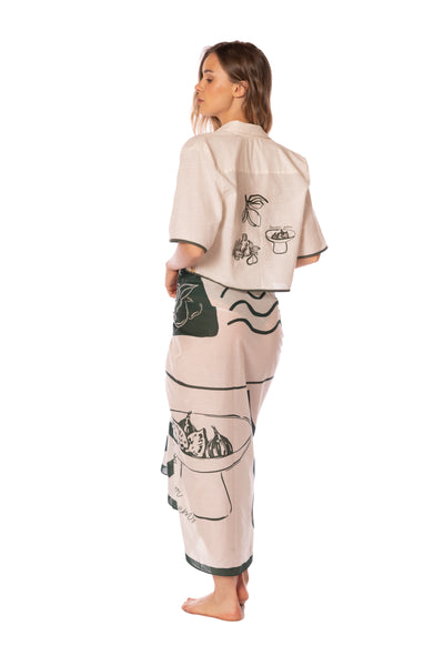 Woman wearing a beige outfit with black and white designs on a white background