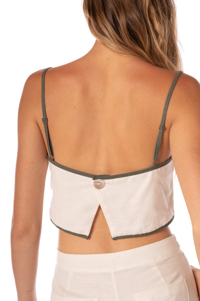Woman wearing a beige crop top with thin straps on a white background