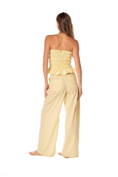 Woman wearing a yellow strapless top and wide-leg pants on a white background