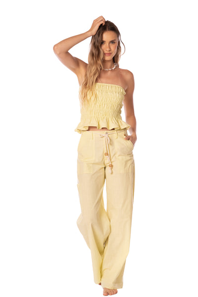 Woman wearing a yellow strapless top and pants on a white background
