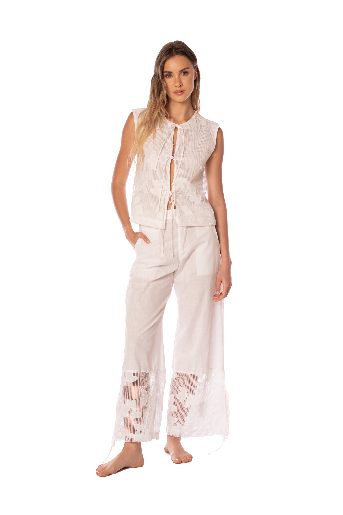 Woman wearing a light-colored outfit with sheer details on a white background