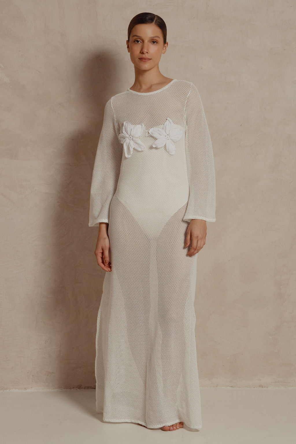 Model wearing white mesh Coral Flora maxi dress with floral appliqués on bust.