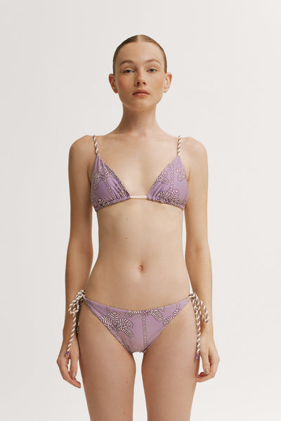 Woman wearing a purple bikini with intricate patterns on a plain background