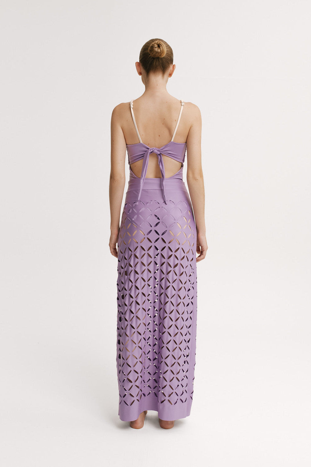 Back view of woman wearing and one piece and a Skirt in lavender with full-length cut-out pattern 