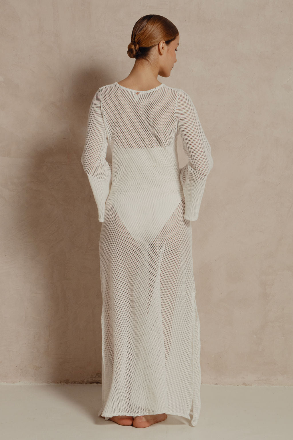 Back view of white long-sleeve mesh maxi dress showing sheer open-weave fabric.