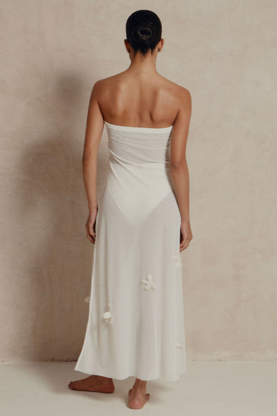 Woman wearing a white strapless dress against a plain background