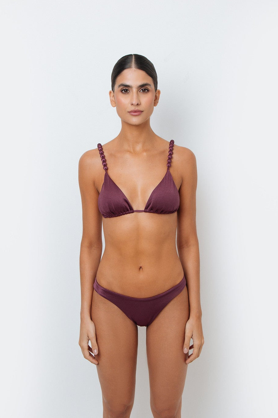 Woman wearing a maroon bikini set against a white background